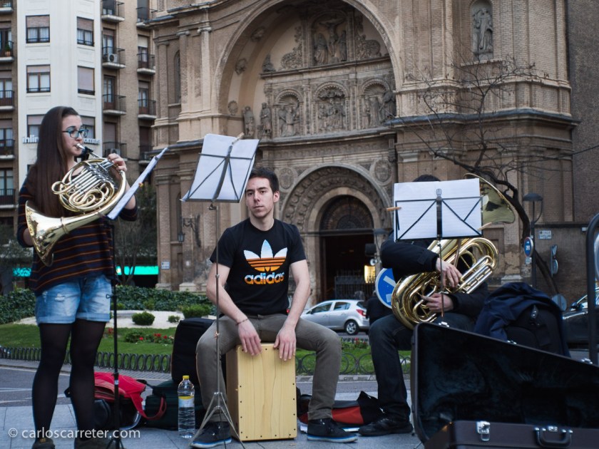 La música tiene gran importancia en la historia entre los dos protagonistas. Y últimamente por Zaragoza, encontramos muchos grupitos de jóvenes músicos, estudiantes de conservatorio, convertidos en músicos callejeros, porque las cosas deben andar realmente mal. Como este grupo de metales en Santa Engracia. Por cierto que la música era una de las "artes liberales". Curiosamente, encuadrada en el "quadrivium", junto con la aritmética, la geometría y la astronomía. No con el "trivium" que era más de letras como los protagonistas de esta historia. Qué cosas.