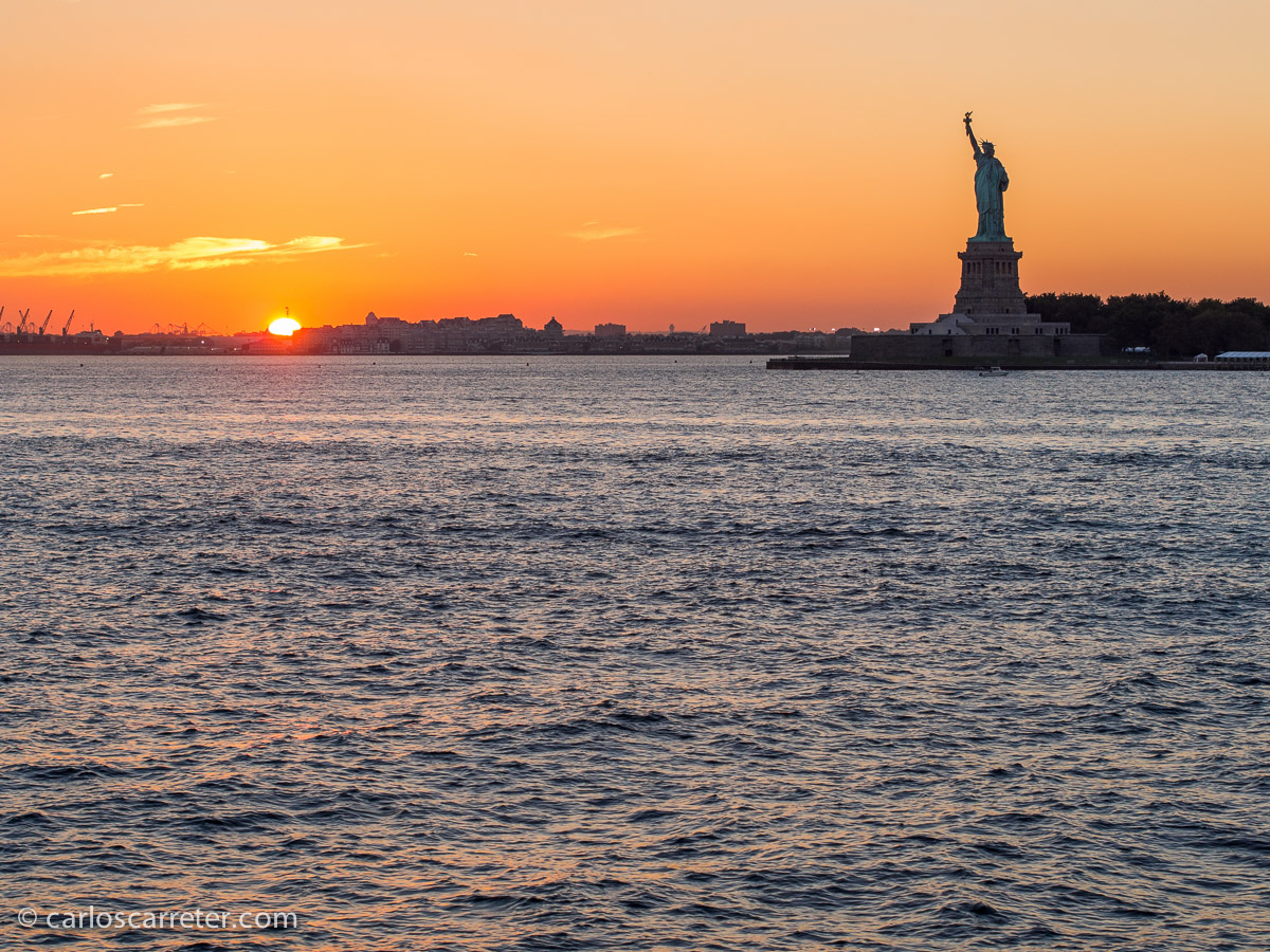 Puesta de sol desde el ferry de Staten Island, con la silueta característica de la estatua de la Libertad.