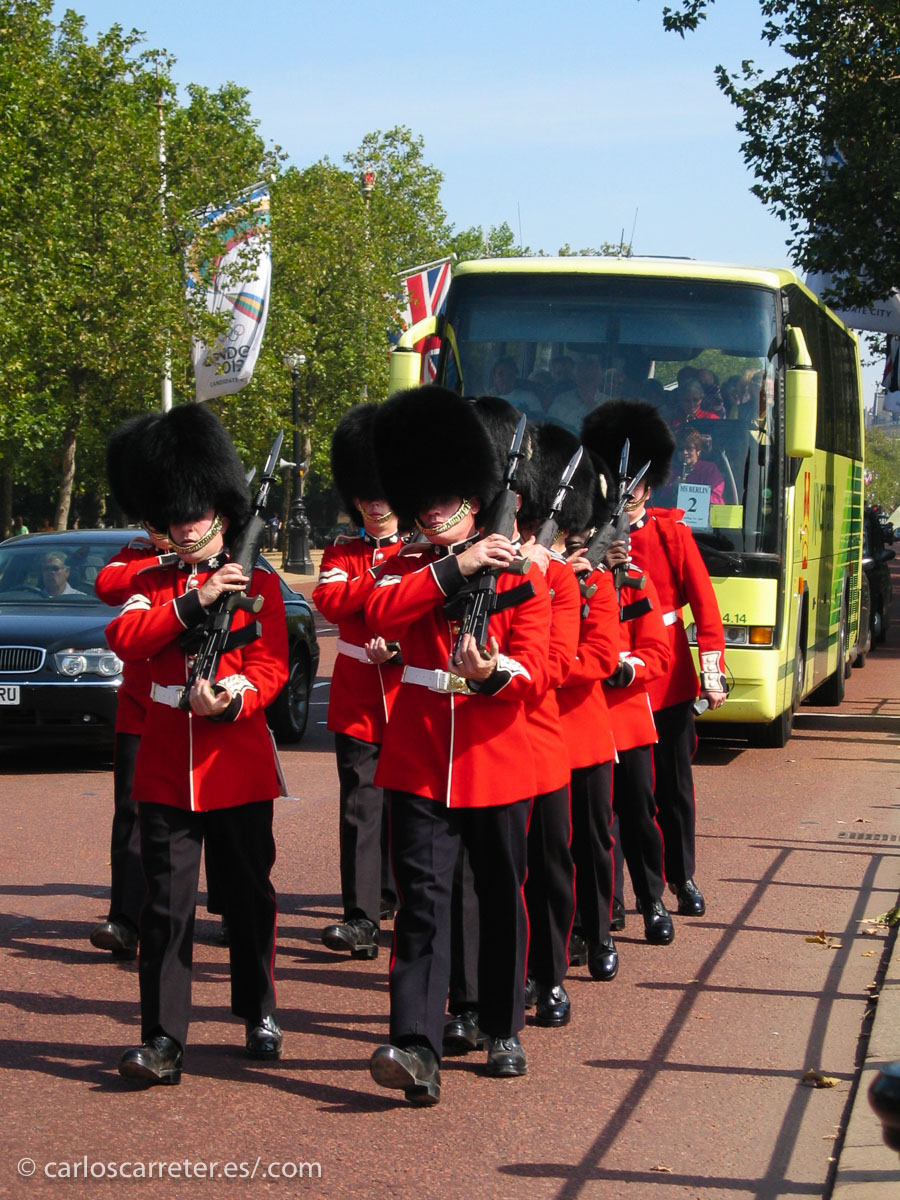 Uno soldados de la guardia de Buckingham Palace atascan el tráfico el Mall londinense.